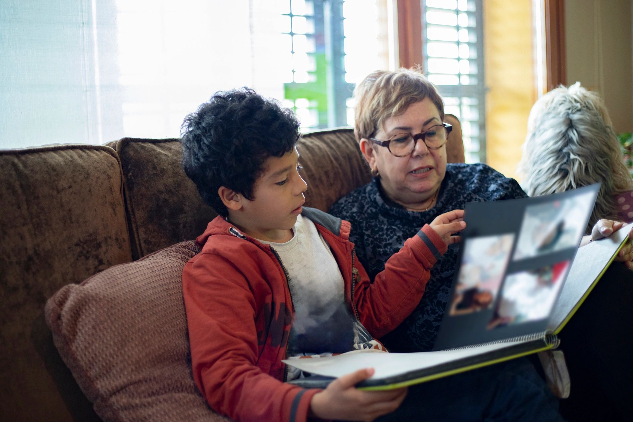 Grandmother and grandson looking through a family photo album