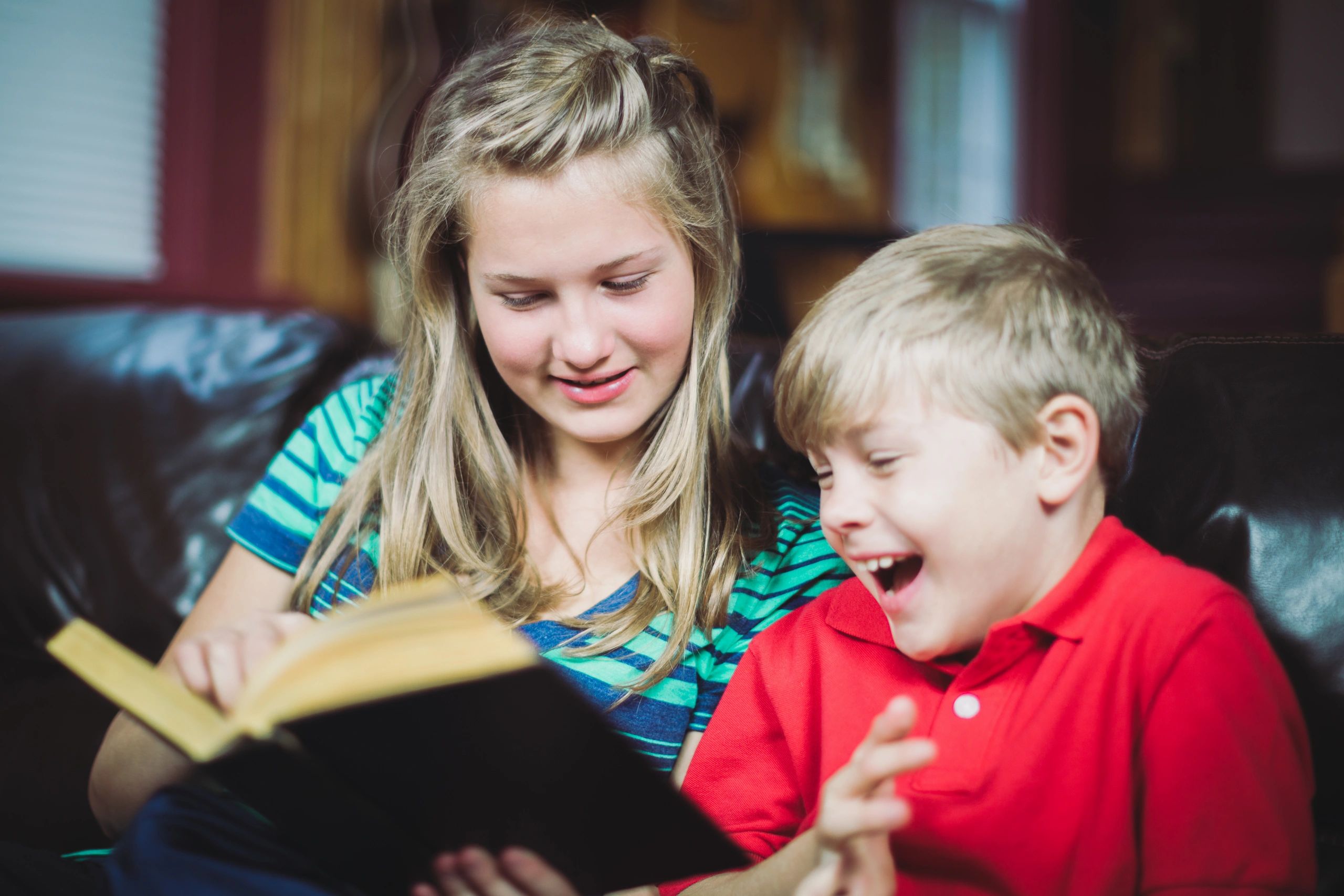 Siblings reading together on a sofa